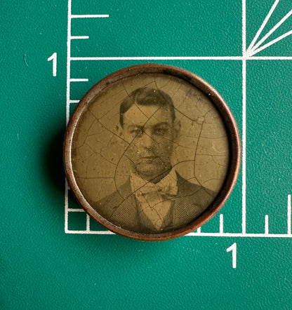 Vintage photograph of a man in a bow tie on a green background with measurement markings.